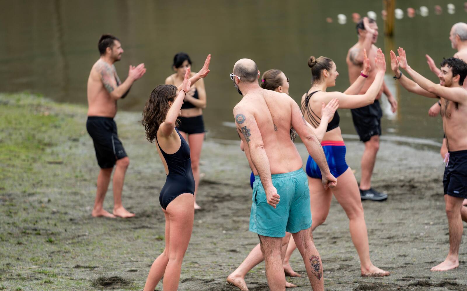 People high fiving each other on the sand as they come out of the lake